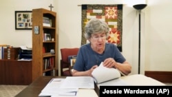 Sister Barbara McCracken looks through prior resolutions filed against various corporations, including Alphabet, Meta, Netflix and Chevron, at the Mount St. Scholastica Benedictine monastery in Atchison, Kan., Tuesday, July 16, 2024. (AP Photo/Jessie Wardarski)