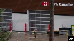 A man wearing chest waders walks through floodwaters in a mall parking lot following a major rain event in Halifax, Nova Scotia, Canada, July 22, 2023.