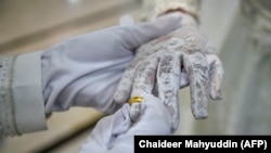 Pengantin pria menyematkan cincin di tangan pengantin wanita dalam akad nikah di sebuah masjid di Banda Aceh, 3 Juni 2020. (Foto: Chaideer Mahyudin/AFP)