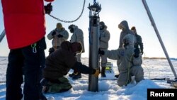 A prototype of a robot built to access underwater areas where Antarctic ice shelves meet land is lowered though the ice during a field test north of Alaska, in March. (US NAVY/SCOTT BARNES/Handout via REUTERS) 