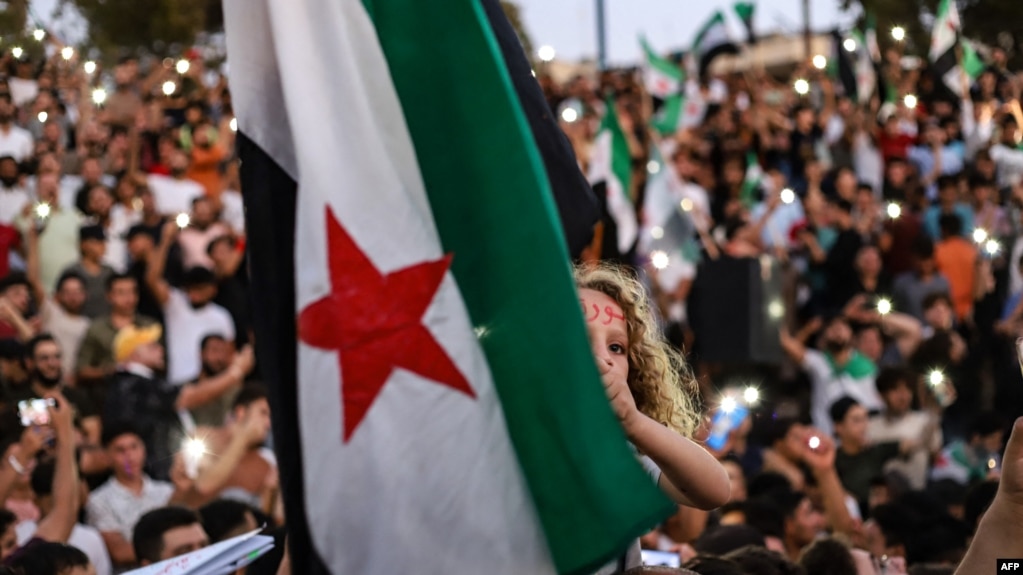 FILE - A girl raises the Syrian opposition flag in Idlib, Aug. 25, 2023, in support of anti-government protests in the southern city of Sweida. More protests occurred March 1, 2024, across Syria's northwest against that region's jihadi rulers.