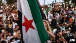 FILE - A girl raises the Syrian opposition flag in Idlib, Aug. 25, 2023, in support of anti-government protests in the southern city of Sweida. More protests occurred March 1, 2024, across Syria's northwest against that region's jihadi rulers.