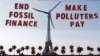 This photograph shows a replica of a wind turbine on a net reading 'End fossil finance, make polluters pay' as activists demonstrate against fossil finance on the Trocadero Plaza in Paris, on the eve of the Summit for a New Global Financial Pact. 