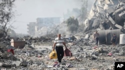 Palestinians walk by the buildings destroyed in the Israeli bombardment on al-Zahra, on the outskirts of Gaza City.&nbsp;(AP Photo/Ali Mahmoud)