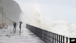 People run from crashing waves at the promenade in Folkestone, England, Nov, 2, 2023, as Storm Ciaran brings high winds and heavy rain along the south coast of England.