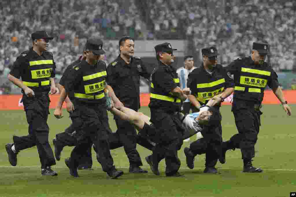 Security guards remove a pitch invader during the friendly soccer match between Argentina and Australia at Workers&#39; Stadium in Beijing, China.