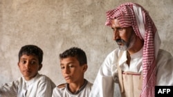 Nasser Jabbar bersama kedua anaknya duduk di rumah mereka yang terletak di pinggiran Kota Nasiriyah, provinsi Dhi Qar, Irak, pada 25 September 2023. (Foto: AFP/Asaad Niazi)