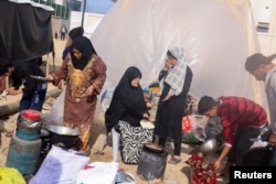 Displaced Palestinians, who fled their houses due to Israeli strikes, prepare to bake bread next to a tent, at a camp in Rafah in the southern Gaza Strip, Dec. 10, 2023.