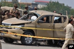 FILE - Pakistani security officers examine a damaged vehicle at the site of a roadside bombing in Peshawar, Pakistan, on Sept. 11, 2023.