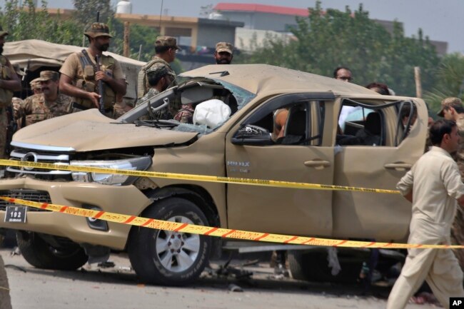 FILE - Pakistani security officers examine a damaged vehicle at the site of a roadside bombing in Peshawar, Pakistan, on Sept. 11, 2023.