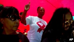 FILE - A woman dances as she listens to music while attending a World AIDS Day commemoration at Nkosi's Haven in Johannesburg on Nov. 30, 2019, on the eve of World AIDS Day.