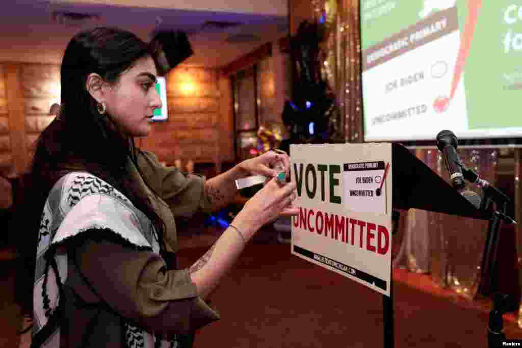 Activist Natalia Latif tapes a Vote Uncommitted sign on the speaker's podium during an uncommitted vote election night gathering as Democrats and Republicans hold their Michigan primary presidential election, in Dearborn, Feb. 27, 2024.