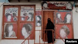 FILE - A woman wearing a niqab enters a beauty salon where the ads of women have been defaced by a shopkeeper in Kabul, Oct. 6, 2021.