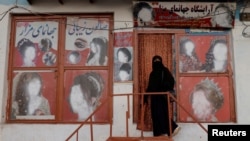 FILE - A woman wearing a niqab enters a beauty salon where the ads of women have been defaced by a shopkeeper in Kabul, Oct. 6, 2021. 