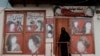 FILE - A woman wearing a niqab enters a beauty salon where the ads of women have been defaced by a shopkeeper in Kabul, Oct. 6, 2021. 