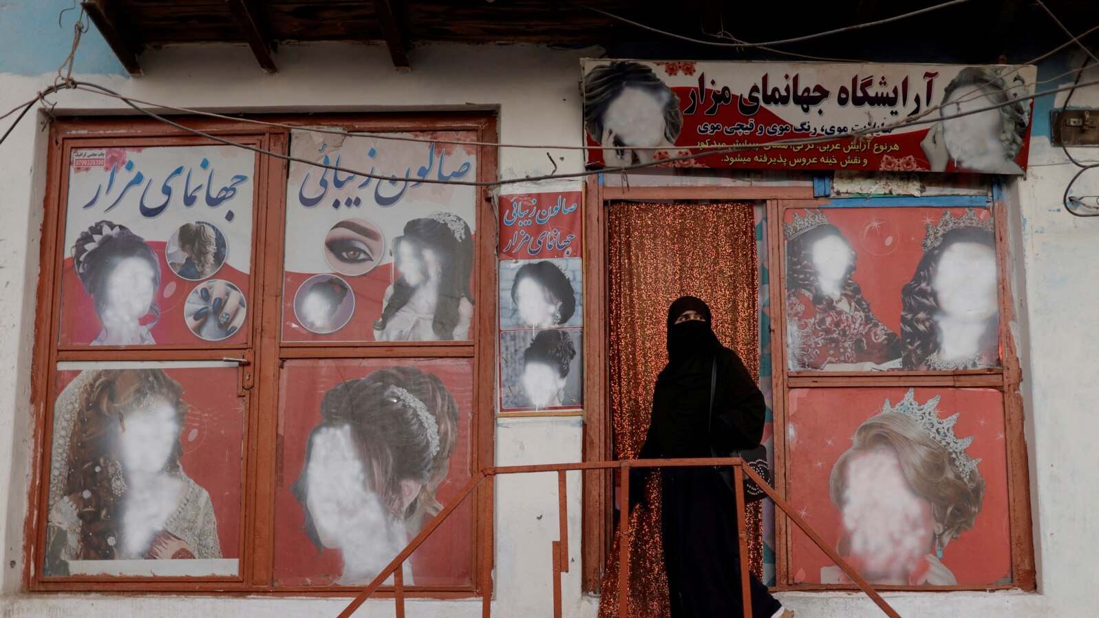 FILE - A woman wearing a niqab enters a beauty salon where the ads of women have been defaced by a shopkeeper in Kabul, Oct. 6, 2021. 