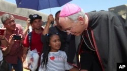 El Paso Catholic Bishop Mark Seitz talks with Celsia Palma, 9, of Honduras, as they walk to the Paso Del Norte International Port of Entry, June, 27, 2019, in Juarez, Mexico.