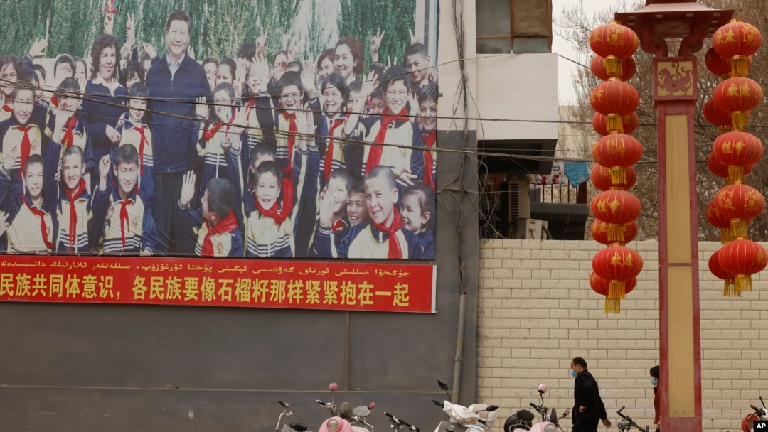 FILE — A sign features slogans calling for unity among ethnicities in Shule county in China's Xinjiang Uyghur Autonomous Region, March 20, 2021. Activists are criticizing China's law on ethnic embedding in Xinjiang as the first step in legalizing China's assimilation policies.