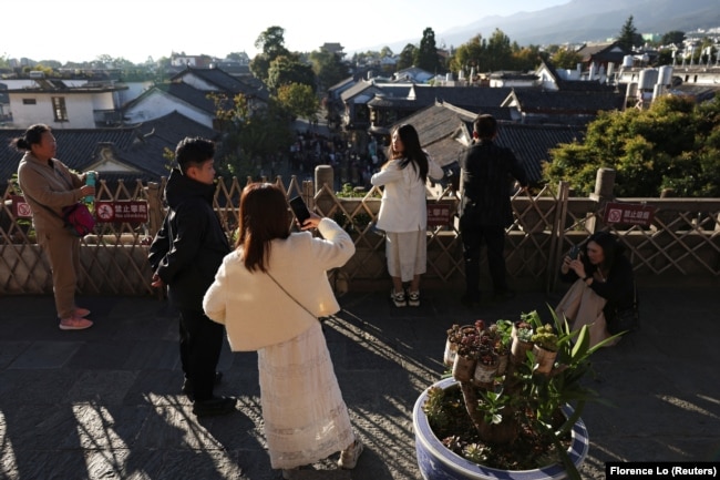 Visitors take pictures at a tower overlooking the old town of Dali, Yunnan province, China November 11, 2023. (REUTERS/Florence Lo)