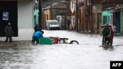 En esta imagen distribuida por la Agencia Cubana de Noticias, se ve a personas en una calle después de que las fuertes lluvias provocaran una inundación en Camagüey, Cuba, el 9 de junio de 2023.