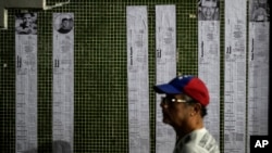 Presidential election tallies, or "actas," stream down a wall with the faces of prisoners detained amid a government crackdown, during a vigil in Caracas, Venezuela, Aug. 8, 2024.