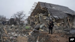 Un residente local toma una fotografía del cráter de un misil y los escombros de una casa privada arruinada por el ataque con misiles rusos en Kiev, Ucrania, el lunes 11 de diciembre de 2023.