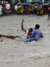 FILE - A man attempts to rescue a boy from raging floodwaters following heavy rains in Mogadishu, Somalia, Nov. 9, 2023. Farah Omar Nur, the secretary general of the Federation of Somali Journalists, says environmental journalism is not easy, especially in Somalia.