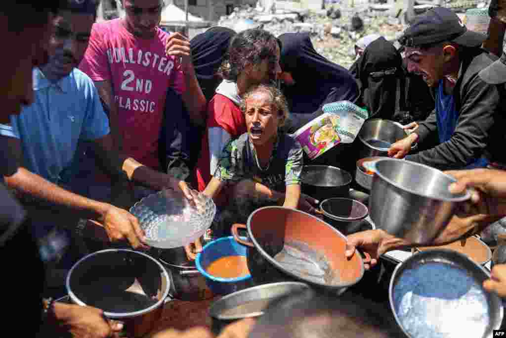 A child reacts as people gather to receive meals during food distribution from a kitchen in the Bureij camp for Palestinian refugees in the central Gaza Strip.