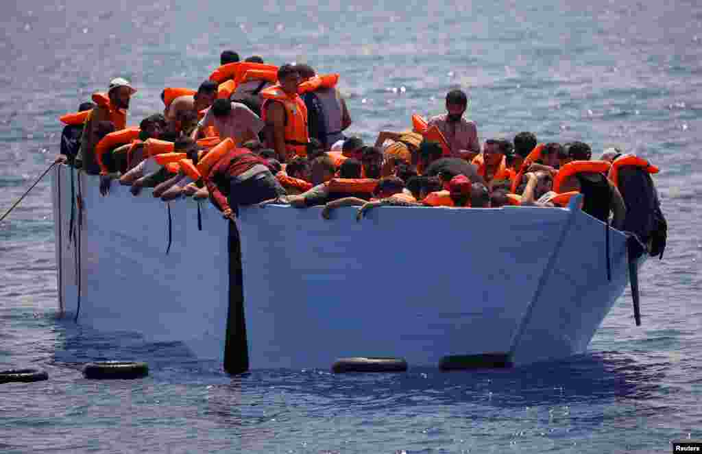 Migrants stands on a wooden boat near NGO Open Arms rescue boat &quot;Astral&quot; in international waters south of Lampedusa, in the Mediterranean Sea.