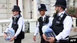 Polisi membawa tabung nitro oksida, yang dikenal sebagai gas tawa, yang disita dari warga yang berencana menggunakannya sebagai narkoba, selama Karnaval Notting Hill di London barat, 29 Agustus 2022. (Susannah Irlandia / AFP)