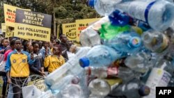 Climate activists hold banners and chant slogans in front of a plastic installation as they march to demand drastic reduction in global plastic production ahead of the third meeting of the Intergovernmental Negotiating Committee (INC-3) in Nairobi on November 11, 2023.