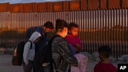 FILE - Migrants from Brazil wait to be processed by US Border Patrol agents after passing through a gap in the border wall from Mexico in Yuma, Ariz., June 10, 2021, to seek asylum. 