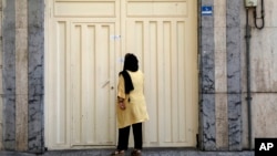 A woman reads the Iranian police closure notice on the gate of a language institute certified by the German embassy, in northern Tehran, Iran, Aug. 20, 2024. 