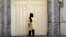 A woman reads the Iranian police closure notice on the gate of a language institute certified by the German embassy, in northern Tehran, Iran, Aug. 20, 2024. 