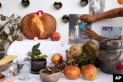 Ana Martínez places a photo on her Day of the Dead altar at her home's terrace in Santa Maria Atzompa, Mexico, Oct. 31, 2023.