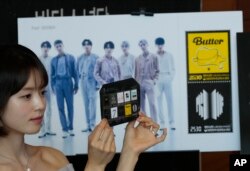 Seorang model menunjukkan selembar prangko menandai peringatan 10 tahun debut band K-pop BTS di kantor pos di Seoul, Korea Selatan, Senin, 12 Juni 2023. (Foto: AP)