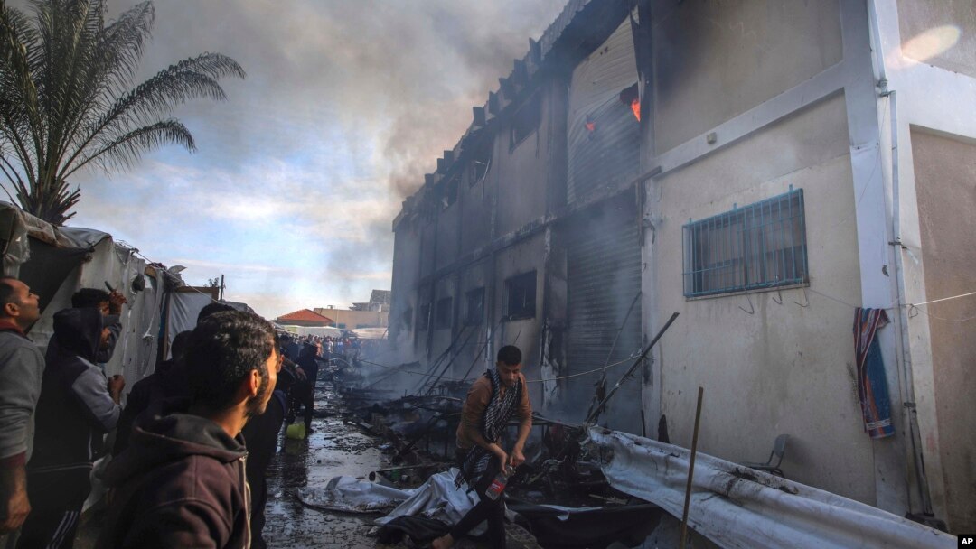 Warga Palestina mencoba memadamkan api di gedung pusat pelatihan kejuruan UNRWA yang digunakan para pengungsi untuk berlindung, setelah menjadi sasaran tank Israel di Khan Younis, Jalur Gaza selatan, Rabu 24 Januari 2024.