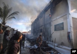 Palestinians try to extinguish a fire at a building of an UNRWA vocational training center which displaced people use as a shelter, after being targeted by Israeli tank shill in Khan Younis, southern Gaza Strip, Jan. 24, 2024.