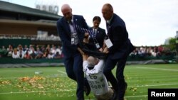 A Just Stop Oil protester is detained by security staff on Court 18 during the first round match between Britain's Katie Boulter and Australia's Daria Saville on July 5, 2023. 