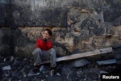 A Palestinian child sits near the site of Israeli strikes on houses after a temporary truce between Palestinian Islamist group Hamas and Israel expired, in Khan Younis in the southern Gaza Strip, Dec. 1, 2023.