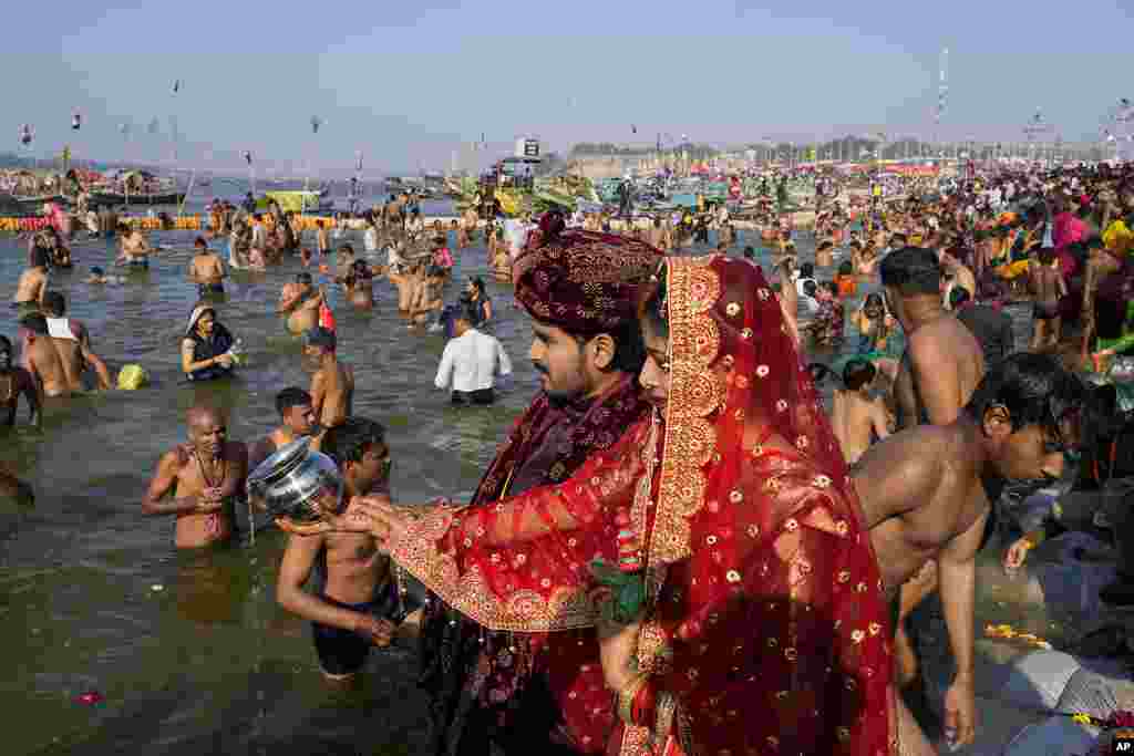 A newly married couple offer prayers as Hindu devotees take dip at the Sangam, the meeting point of the Ganges and the Yamuna rivers, during Shivaratri festival in Prayagraj, India.