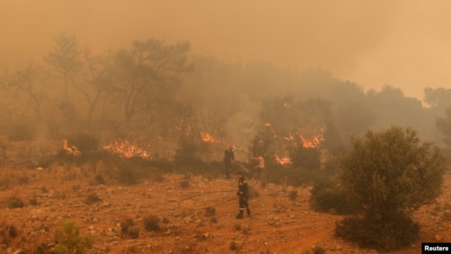 Firefighters try to extinguish a wildfire burning near the village Vlyhada, near Athens, Greece, July 19, 2023.