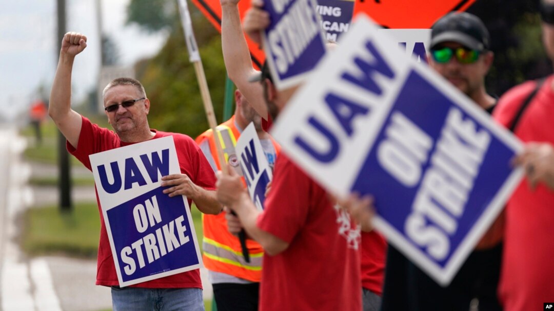 United Auto Workers member Mariusz Mirek holds a picket sign near a General Motors Assembly Plant in Delta Township, Mich., Sept. 29, 2023.