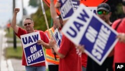 United Auto Workers member Mariusz Mirek holds a picket sign near a General Motors Assembly Plant in Delta Township, Mich., Sept. 29, 2023.