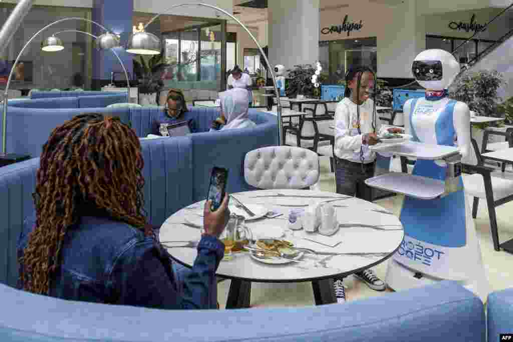 A young patron retreives her meal order from a robotic waiter&#39;s tray at the Robot Cafe, Kenya&#39;s first restaurant to employ humanoid robots as waiters, in Nairob.