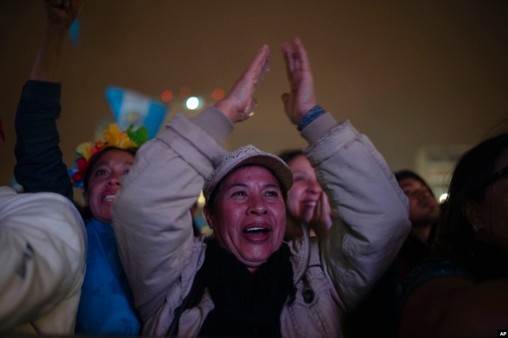  La gente celebra mientras mira la ceremonia de toma de posesión del presidente entrante de Guatemala, Bernardo Arévalo, en una pantalla afuera del Palacio Nacional en la Ciudad de Guatemala, en la madrugada del 15 de enero de 2024. (Foto AP/Santiago Billy)   