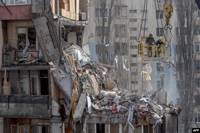 Rescuers clear debris from a multi-story building heavily damaged following a drone strike, in Odesa on March 3, 2024, amid Russia's invasion of Ukraine.
