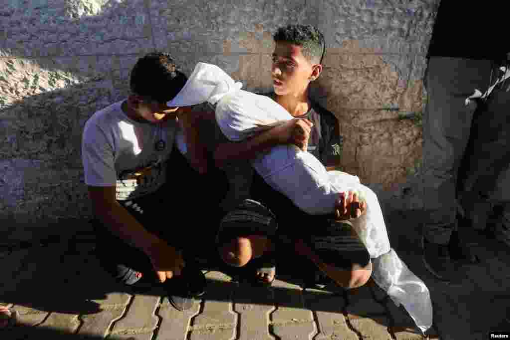 A cousin of a Palestinian child killed in an Israeli strike holds the body in Deir Al-Balah in the central Gaza Strip.