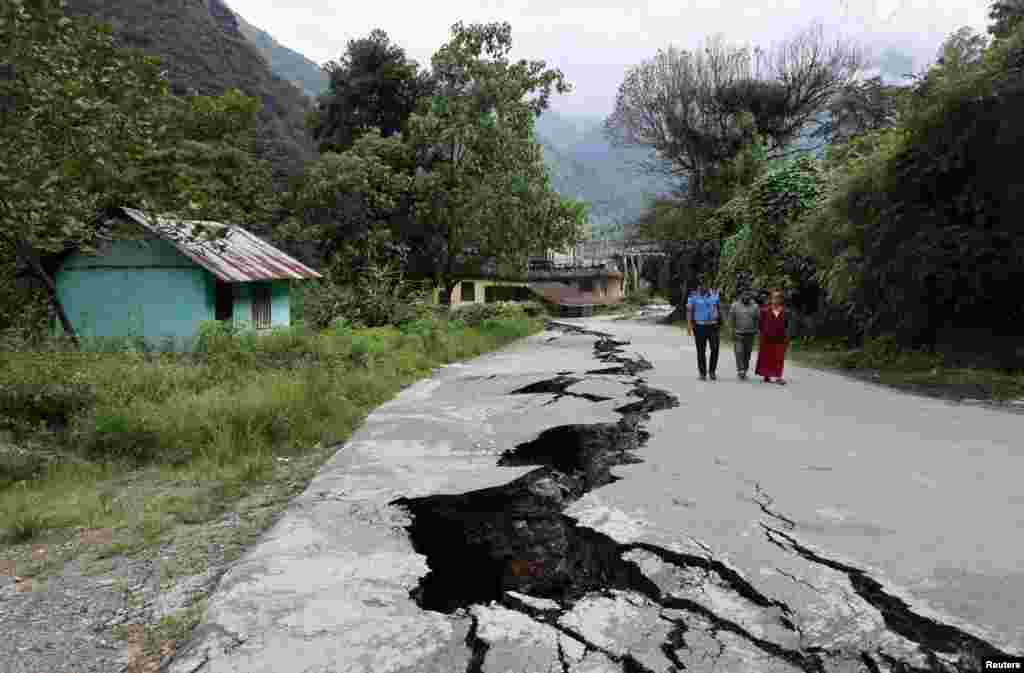 People walk along a road with cracks caused by flash floods in Naga-Namgor village, Sikkim, India. REUTERS/Francis Mascarenhas