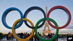 FILE - The Olympic rings are set up in Paris, France, Thursday, Sept. 14, 2017 at Trocadero plaza that overlooks the Eiffel Tower.